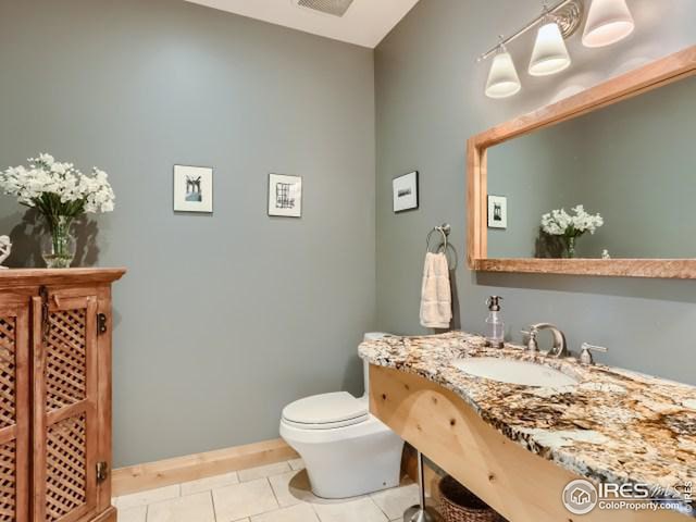 half bath featuring tile patterned flooring, toilet, baseboards, and a sink