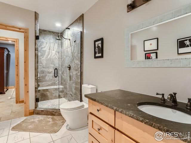 bathroom featuring a shower stall, vanity, toilet, and marble finish floor