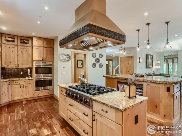 kitchen featuring a kitchen island, appliances with stainless steel finishes, light brown cabinets, and custom range hood