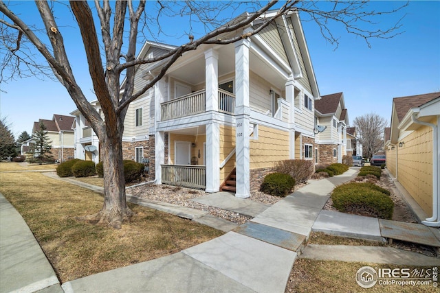 view of side of property featuring a balcony, stone siding, and a residential view