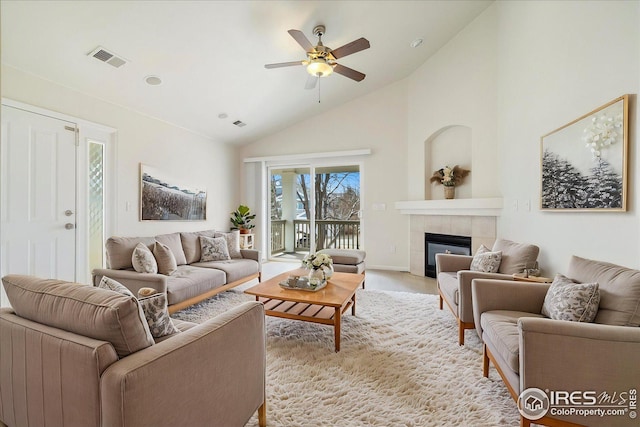 living area featuring high vaulted ceiling, a ceiling fan, visible vents, and a tile fireplace