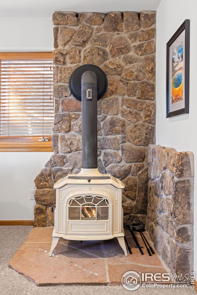 details with baseboards, carpet floors, and a wood stove