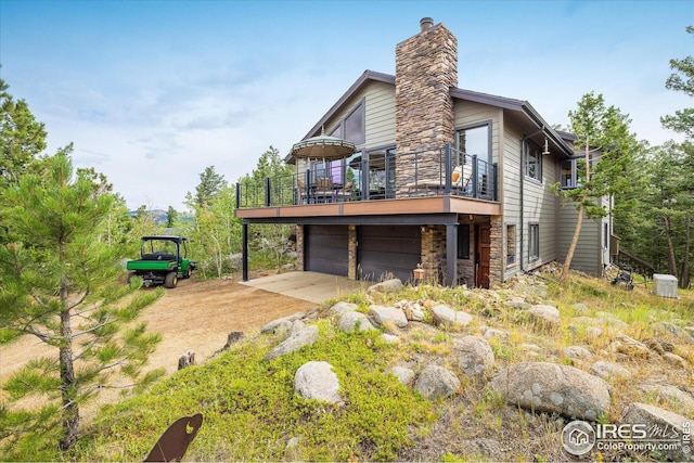 view of home's exterior with a garage, stone siding, a wooden deck, and a chimney