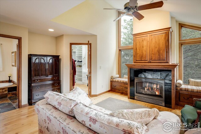 living room featuring baseboards, recessed lighting, a tile fireplace, vaulted ceiling, and light wood-type flooring