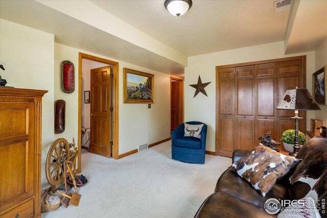 living area featuring light carpet, visible vents, and baseboards