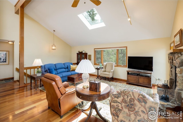 living area featuring beam ceiling, high vaulted ceiling, a skylight, and wood finished floors