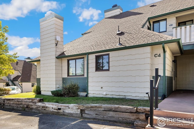 view of side of property featuring roof with shingles and a chimney