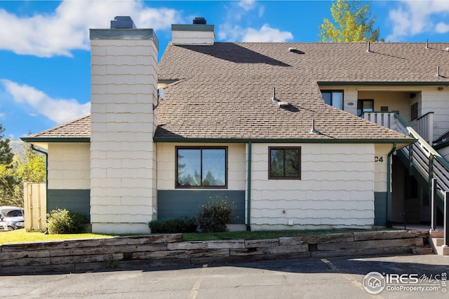 view of side of property with roof with shingles and a chimney