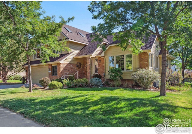 view of front facade with a front yard, roof with shingles, an attached garage, aphalt driveway, and brick siding