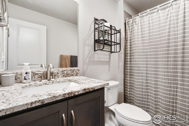 full bath featuring a shower with shower curtain, toilet, and vanity