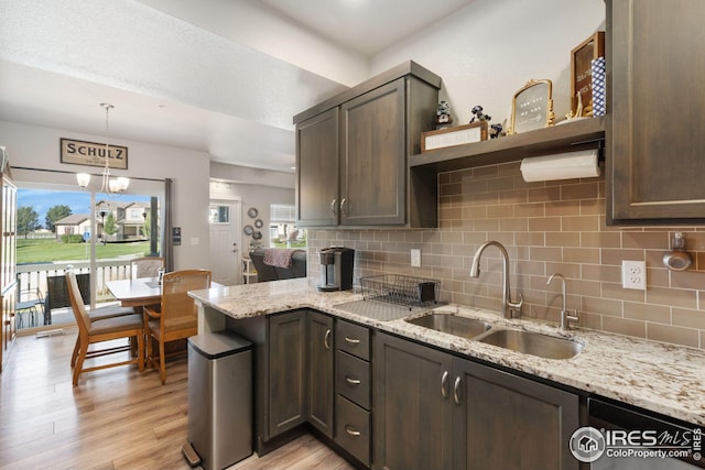 kitchen featuring light stone counters, open shelves, a sink, light wood-style floors, and tasteful backsplash