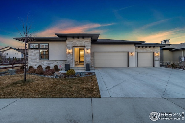 prairie-style home featuring a garage, stone siding, driveway, and stucco siding