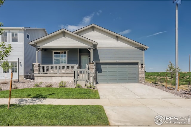 view of front facade featuring a porch, concrete driveway, and stone siding