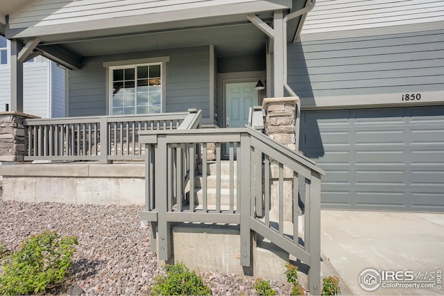 view of exterior entry featuring a garage and covered porch