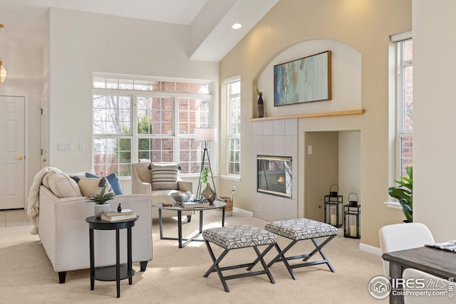 living area featuring a fireplace, plenty of natural light, light colored carpet, and baseboards