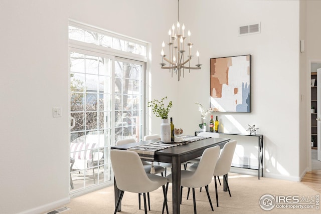 dining area with light colored carpet, baseboards, visible vents, and a chandelier