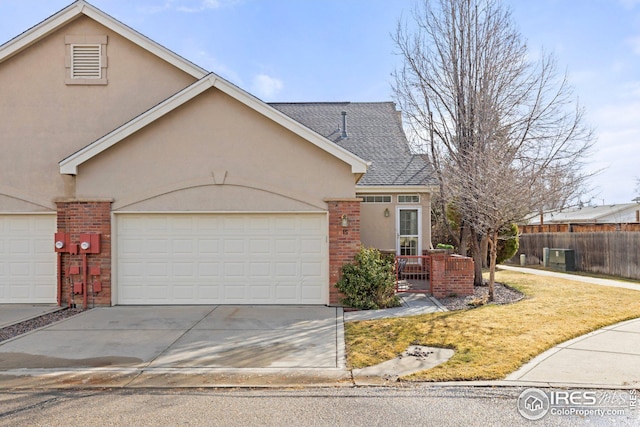 view of front of property featuring brick siding, fence, stucco siding, a garage, and driveway