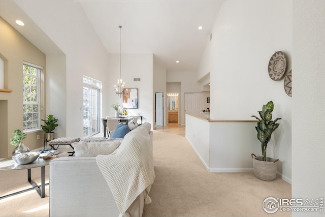 living area featuring baseboards, light carpet, a notable chandelier, and a towering ceiling