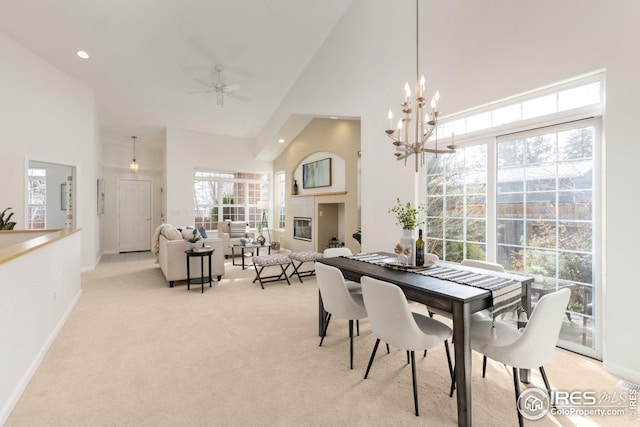 dining area featuring light carpet, a glass covered fireplace, high vaulted ceiling, and baseboards