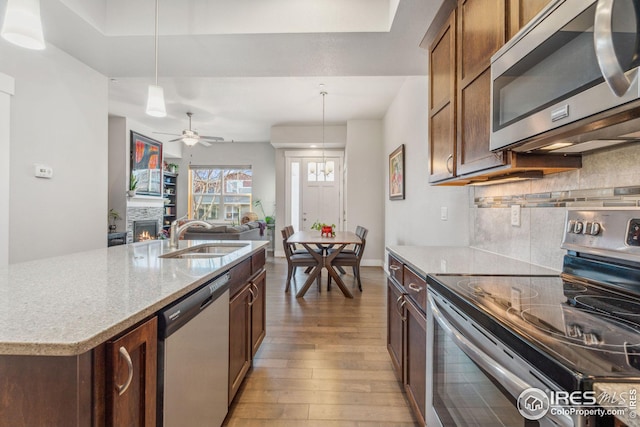 2556 Des Moines Dr Unit 103, Fort Collins, CO 80525 - kitchen with light stone countertops, a sink, decorative backsplash, stainless steel appliances, and light wood-style floors