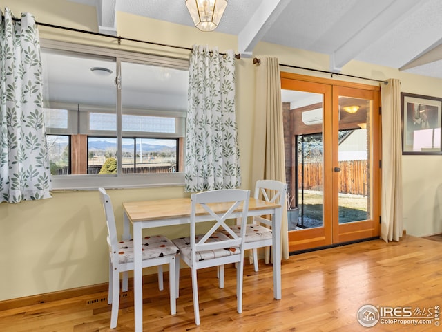 dining area featuring french doors, a textured ceiling, beamed ceiling, and wood finished floors