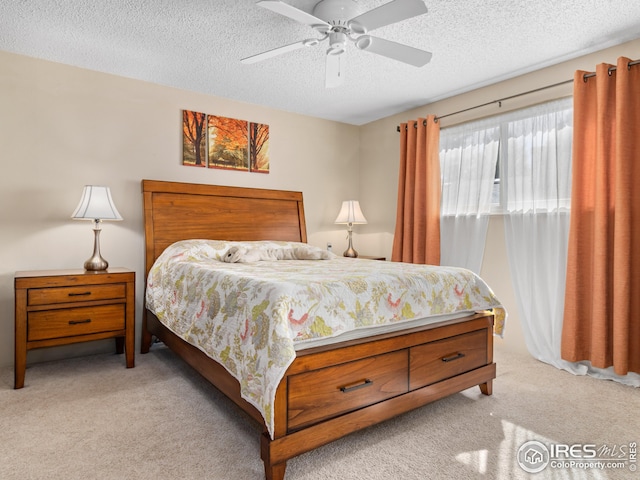 bedroom featuring light colored carpet, a textured ceiling, and a ceiling fan