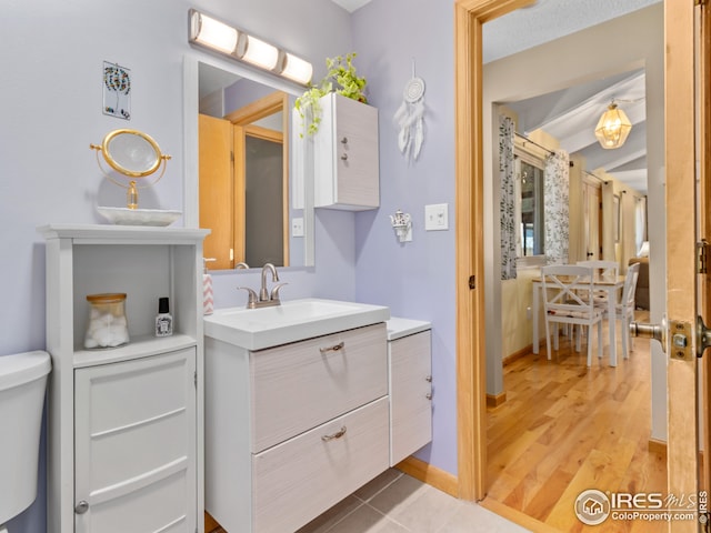 bathroom featuring baseboards, toilet, wood finished floors, and vanity