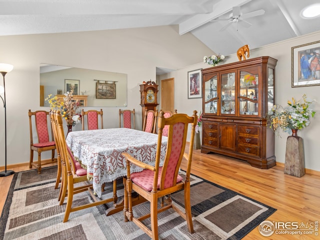 dining area featuring light wood-type flooring, baseboards, a ceiling fan, and vaulted ceiling with beams