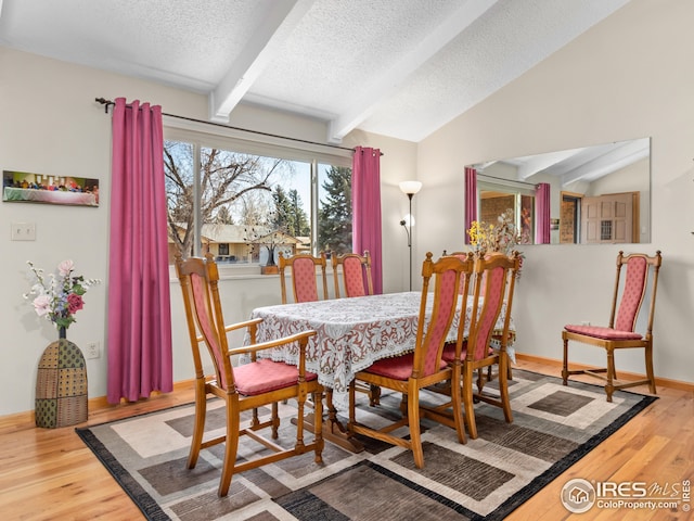 dining area featuring lofted ceiling with beams, baseboards, a textured ceiling, and wood finished floors