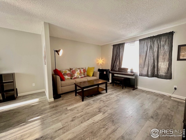 living area with wood finished floors, baseboards, and a textured ceiling