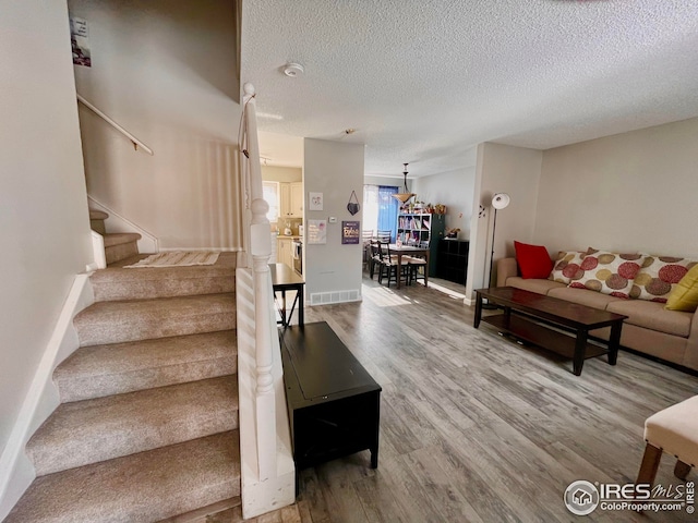 stairway featuring wood finished floors, visible vents, and a textured ceiling