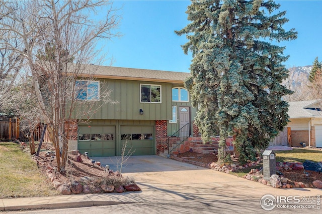 view of front facade featuring fence, an attached garage, brick siding, concrete driveway, and board and batten siding