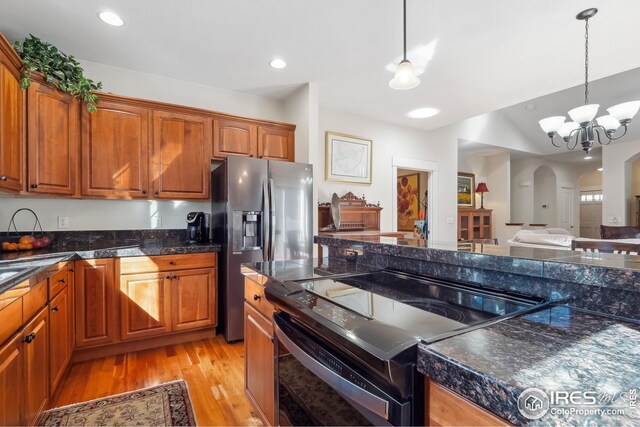 kitchen featuring electric range, arched walkways, stainless steel fridge, and brown cabinets