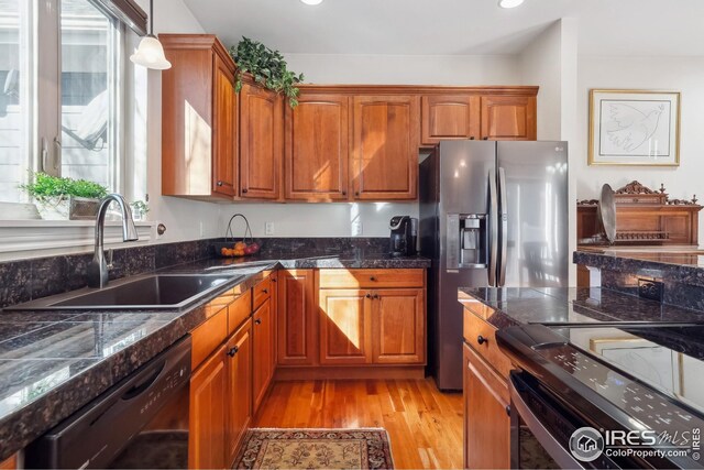 kitchen featuring a sink, stainless steel fridge, dishwasher, and brown cabinetry