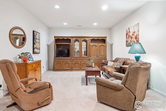 living room featuring recessed lighting, light colored carpet, and baseboards