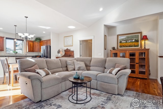living area featuring an inviting chandelier, recessed lighting, wood finished floors, and vaulted ceiling