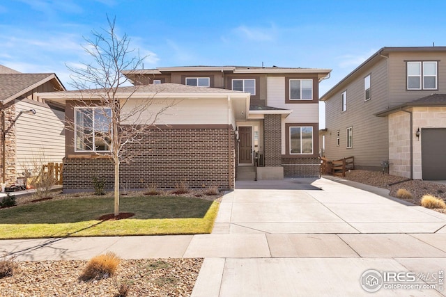 view of front of property with brick siding, a front lawn, and driveway