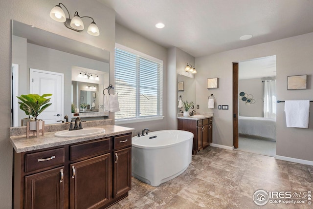 full bath with baseboards, a freestanding tub, two vanities, and a sink