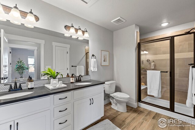 bathroom with a sink, visible vents, a stall shower, and wood finished floors