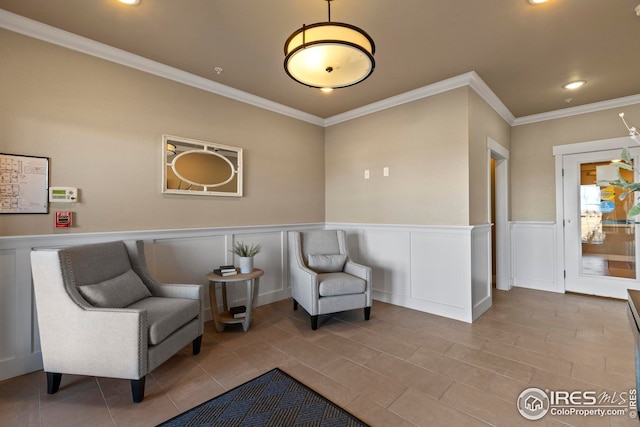 sitting room featuring recessed lighting, a decorative wall, wainscoting, and crown molding