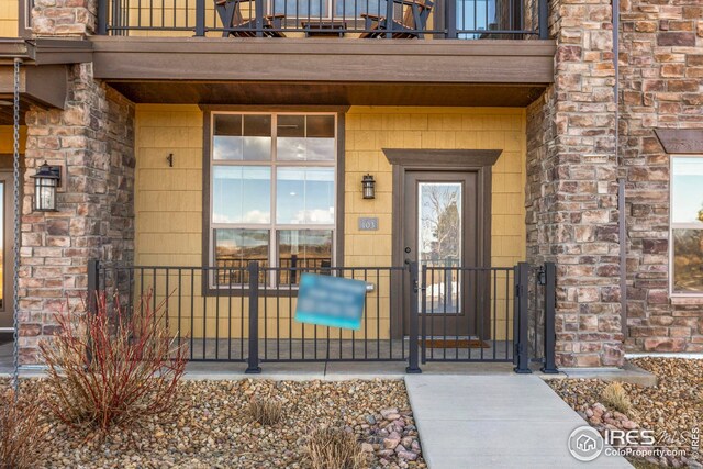 entrance to property with stone siding and a balcony