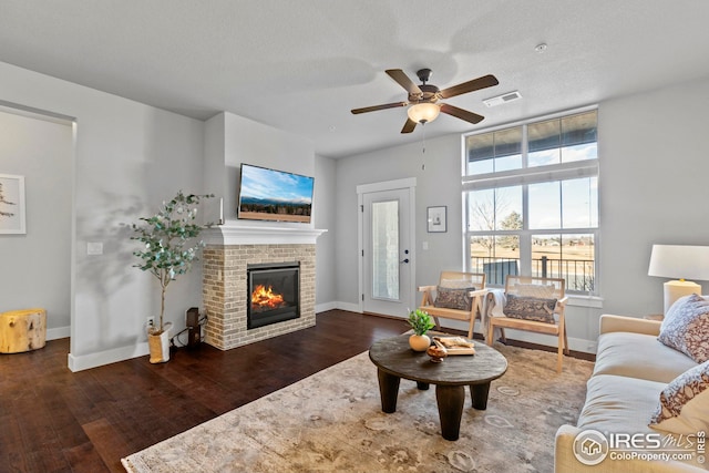 living room featuring visible vents, baseboards, hardwood / wood-style floors, and a fireplace