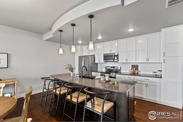 kitchen with dark countertops, stainless steel appliances, tasteful backsplash, and a sink