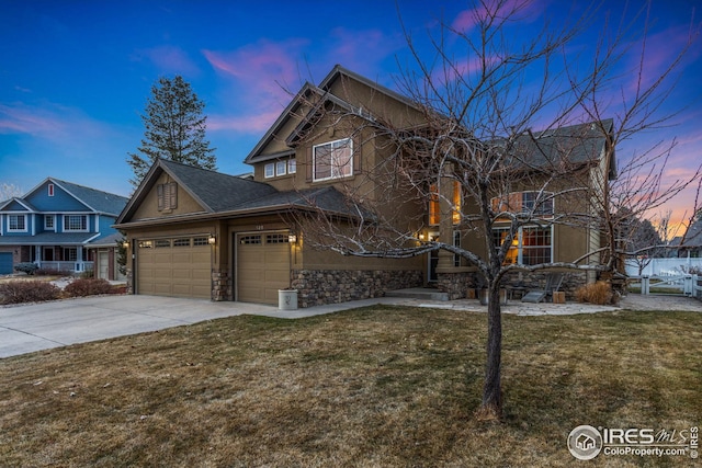 view of front of home with an attached garage, a front yard, stucco siding, stone siding, and driveway