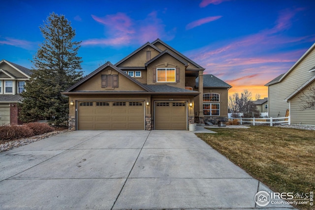 view of front of home featuring stucco siding, stone siding, fence, concrete driveway, and an attached garage