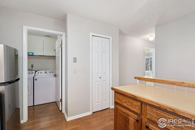 hall featuring wood finished floors, washing machine and clothes dryer, visible vents, and baseboards
