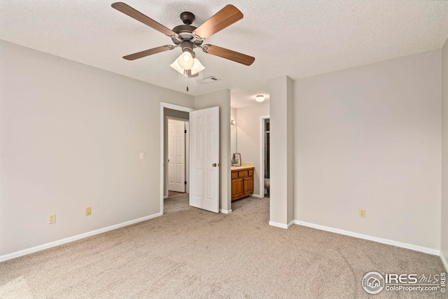 unfurnished bedroom with a textured ceiling, visible vents, ensuite bathroom, baseboards, and light carpet