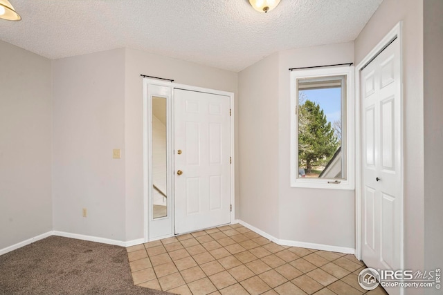 interior space with light tile patterned flooring, a textured ceiling, and baseboards