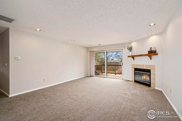 unfurnished living room with a tiled fireplace, an inviting chandelier, carpet floors, visible vents, and a textured ceiling