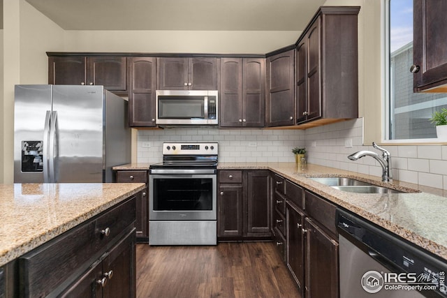 kitchen featuring dark wood-type flooring, light stone counters, appliances with stainless steel finishes, and a sink